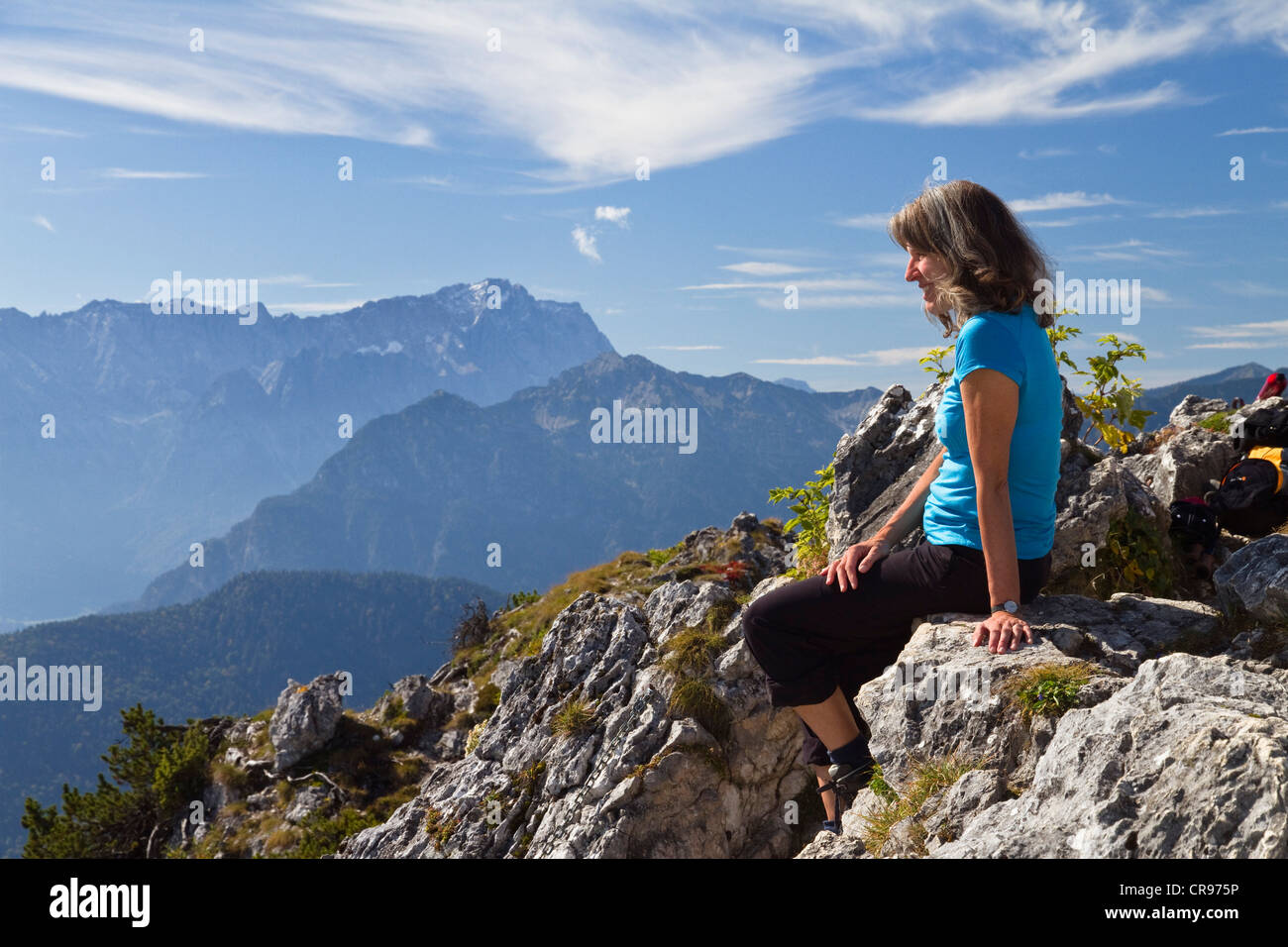 Donna, 45, sulla Ettaler Manndl Mountain, un sotto-picco di montagna Laberberg nelle Alpi Ammergau, guardando verso il Monte Zugspitze Foto Stock