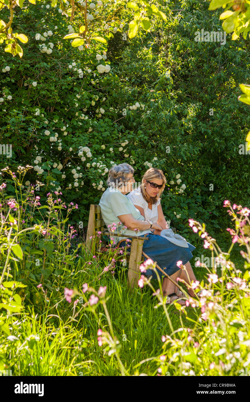 Una donna nel suo 30's parla a sua madre di diritto nel suo 70's in un Regno Unito Garden cottage Foto Stock