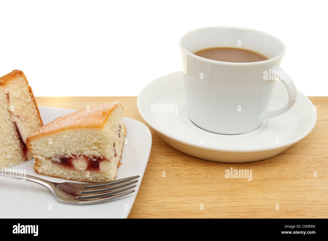 Primo piano di una fetta di lampone pan di spagna e una tazza di caffè su una superficie in legno Foto Stock