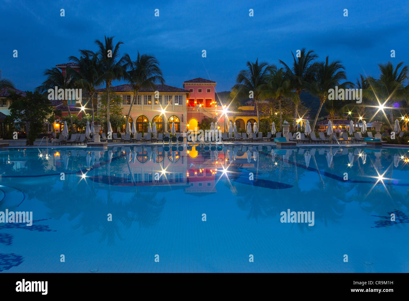 Una grande area piscina accanto a un edificio che mostra il relax dopo una lunga giornata, e anche durante la notte quando il sole va giù. Foto Stock