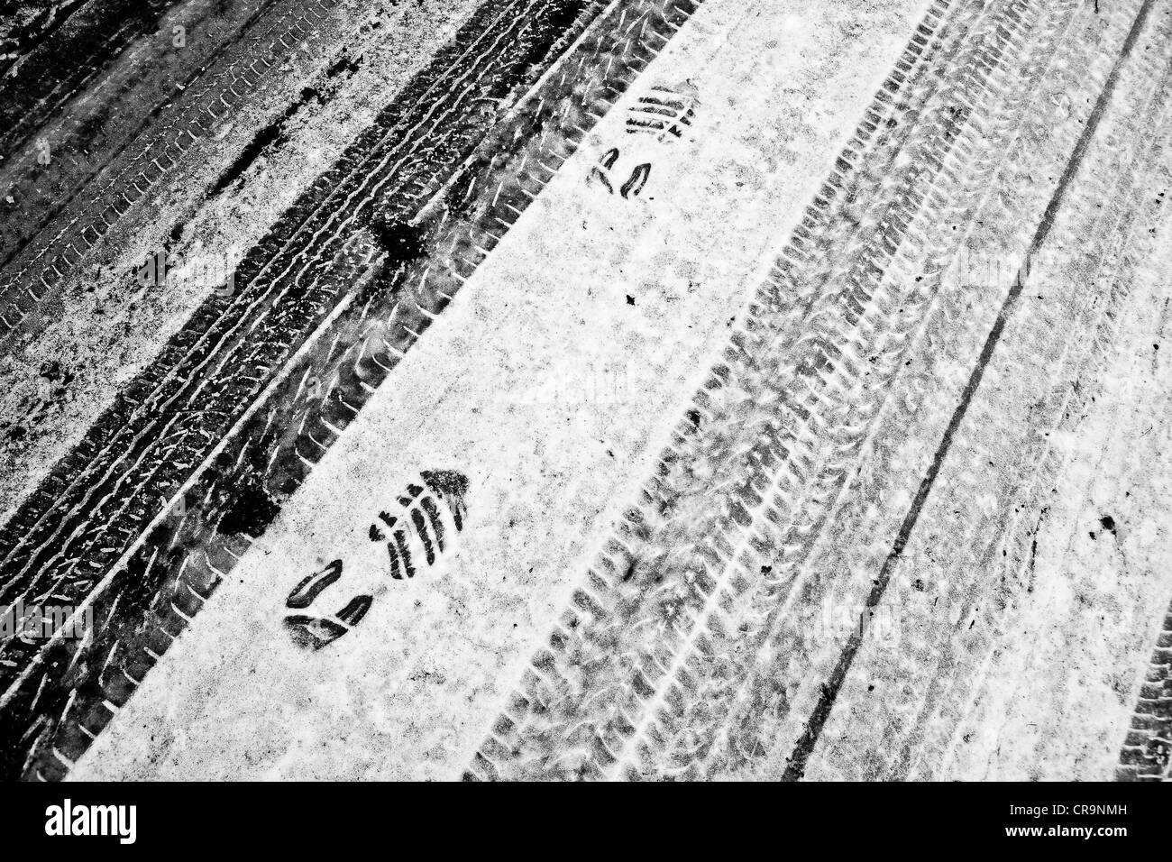 Iced su strada con impronte del battistrada e piede di stampe Foto Stock