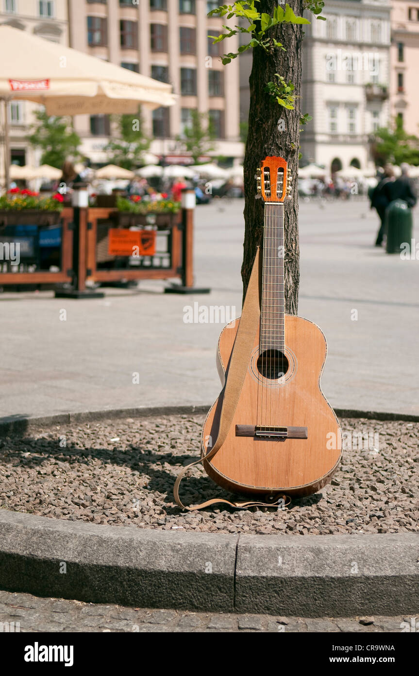 Busker's guitar appoggiata ad albero nella piazza principale del mercato, Cracovia in Polonia. Foto Stock