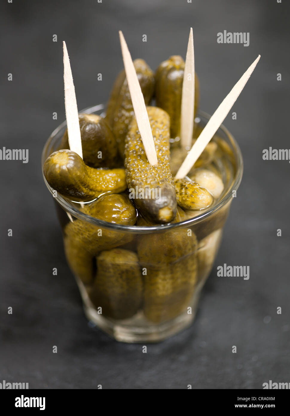 Cetriolini sottaceto o Cornichons in vetro con bastoncini da cocktail Foto Stock