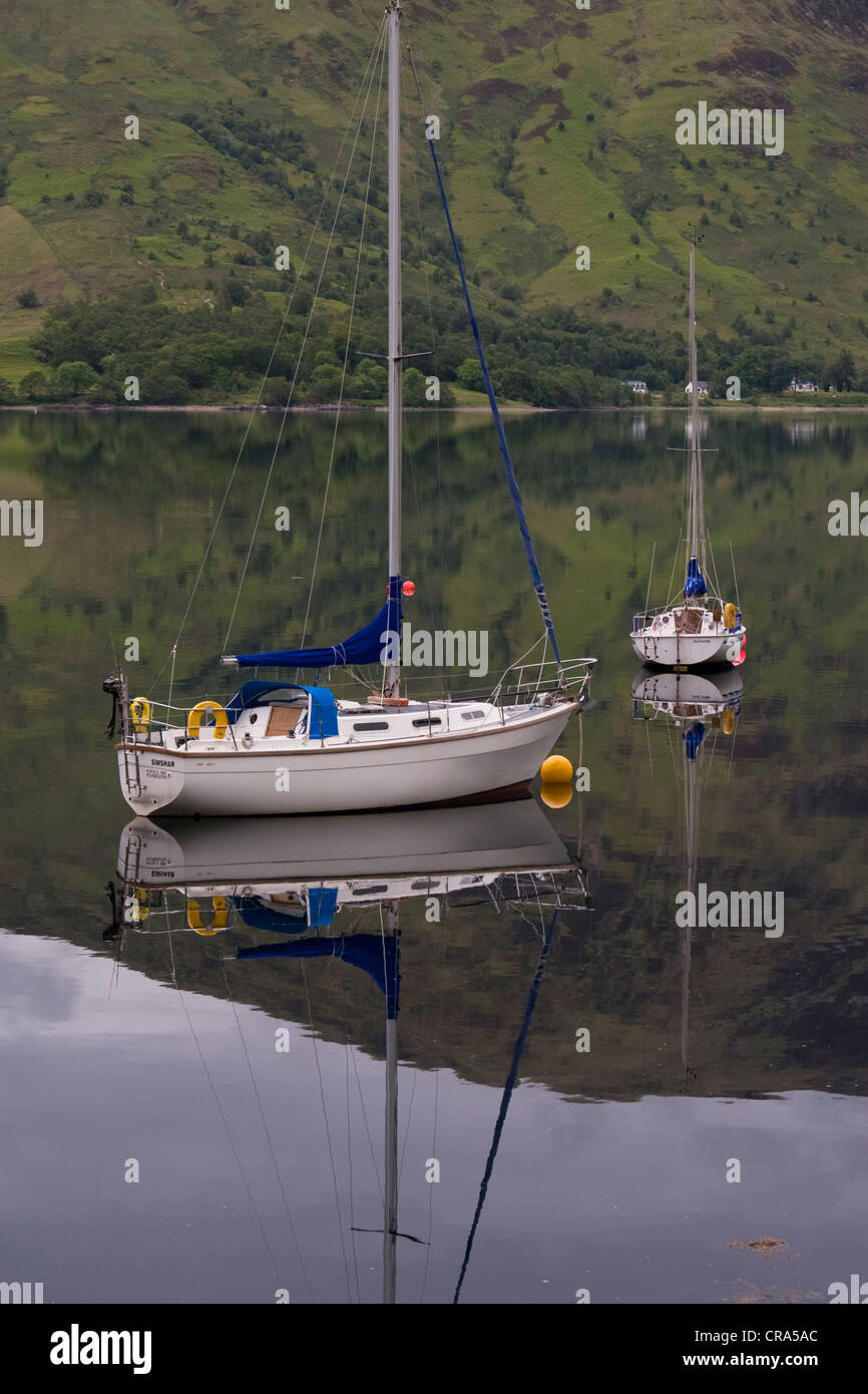 Le barche si riflette sulle calme acque di Loch Leven in Scozia. Foto Stock