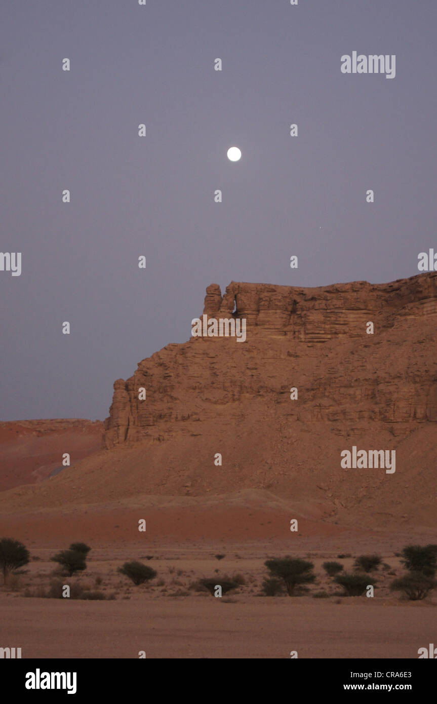 La luna in uscita su formazioni rocciose nella sabbia rossa nel deserto - Riyadh, Regno di Arabia Saudita Foto Stock
