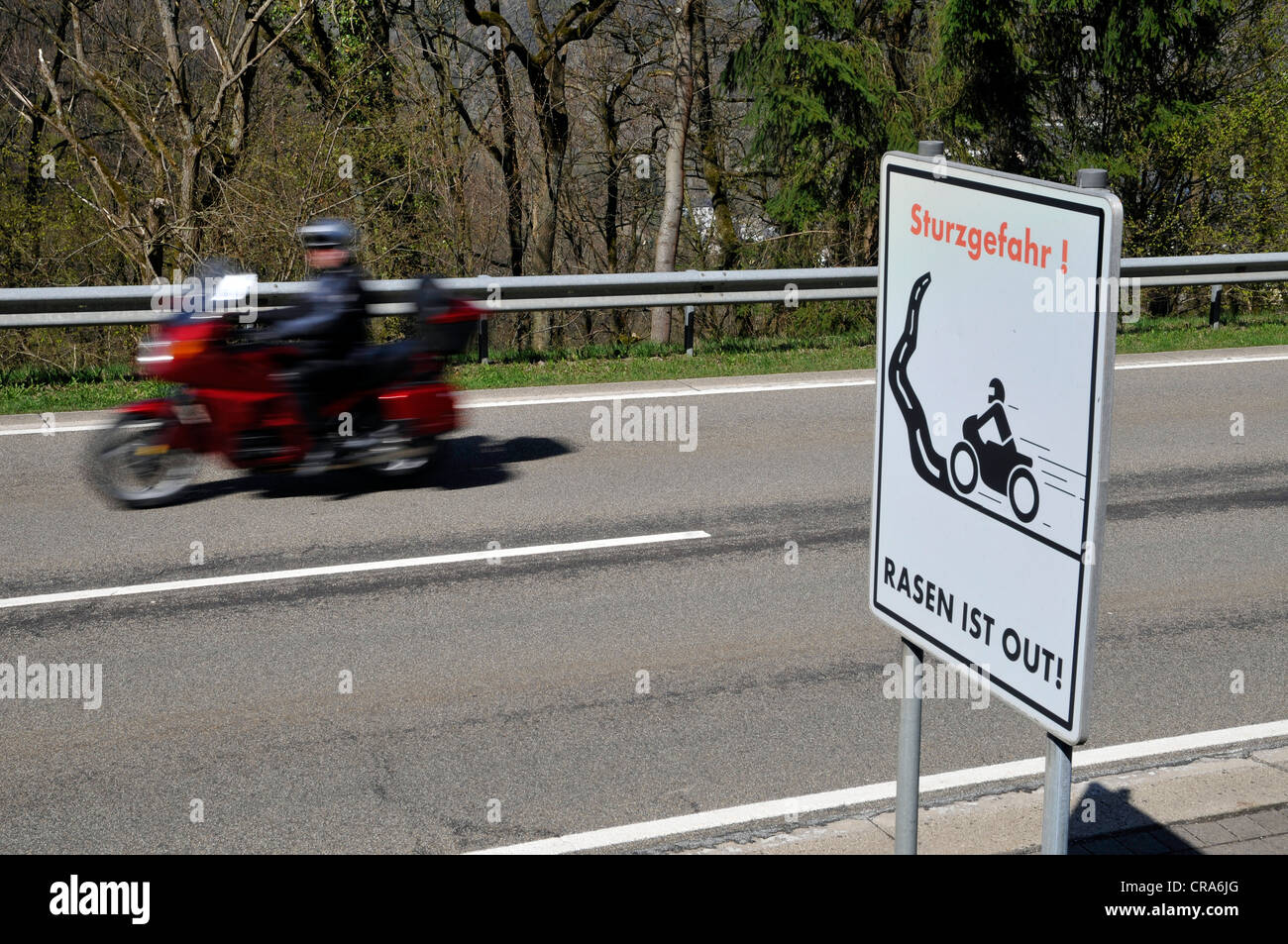 Motociclista sulla strada di un paese con un segnale di avvertimento, Sturzgefahr - Rasun ist, Tedesco per curve pericolose - assenza di accelerazione Foto Stock
