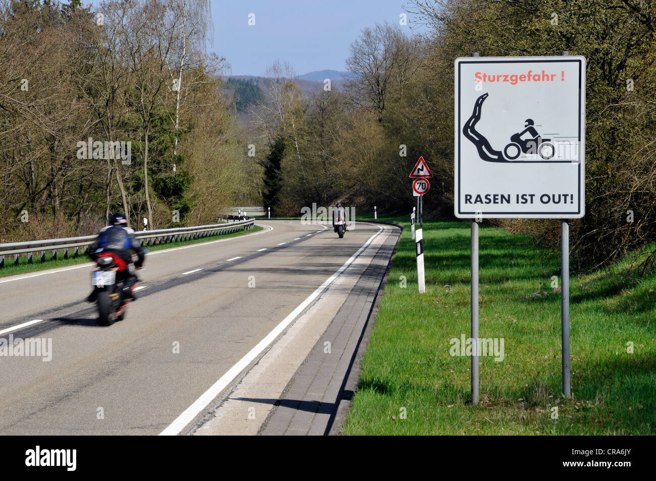 Motociclista sulla strada di un paese con un segnale di avvertimento, Sturzgefahr - Rasun ist, Tedesco per curve pericolose - assenza di accelerazione Foto Stock