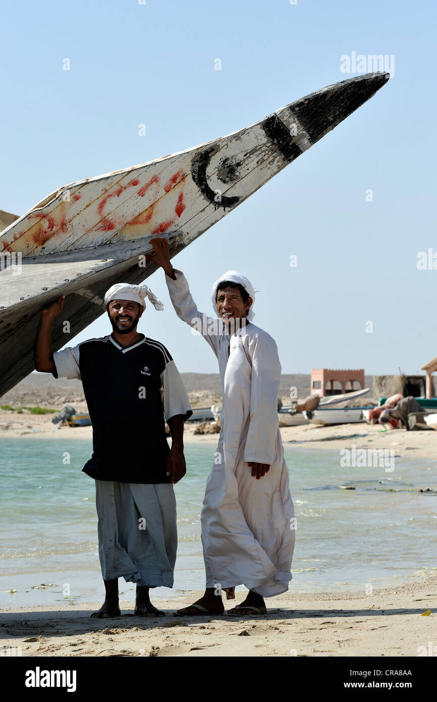 Gli uomini in posa di fronte alla loro barca dhow in Sur, Oman, Medio Oriente Foto Stock