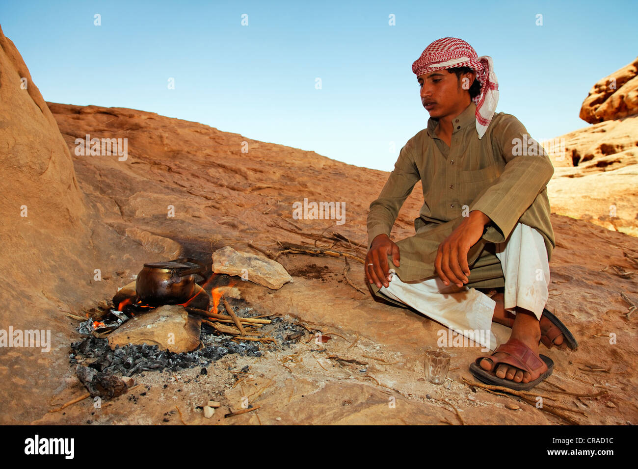 Giovane beduino seduto accanto a un falò nel deserto, Wadi Rum, il Regno hascemita di Giordania, Medio Oriente e Asia Foto Stock