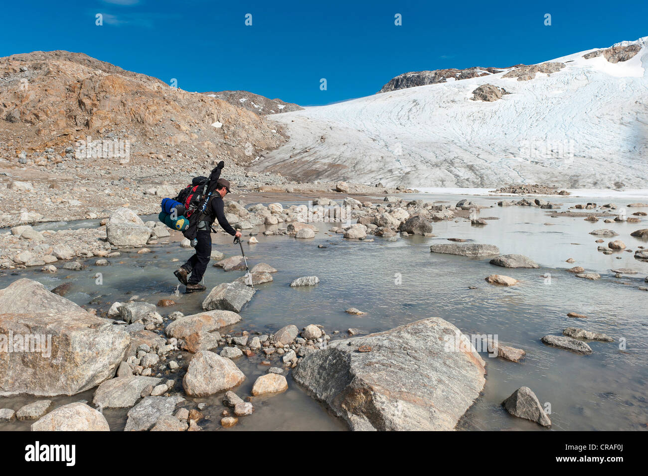 Leader di un gruppo di escursionisti con uno zaino e un fucile al fiume-crossing presso Mittivakkat Glacier, Penisola Ammassalik Foto Stock