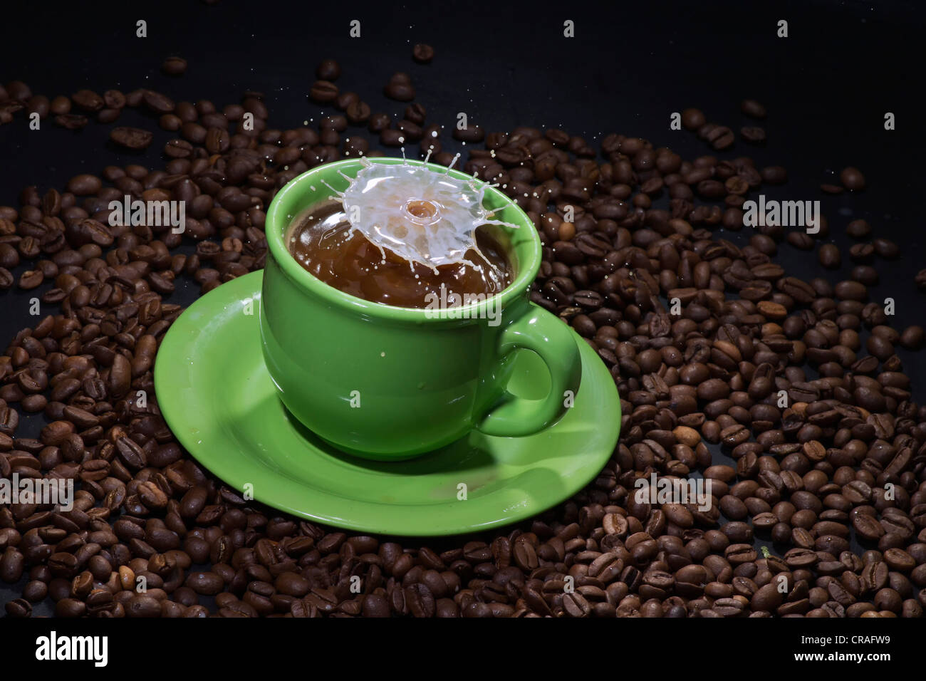 Latte bizzarra scultura di caduta su un verde tazza di caffè Foto Stock