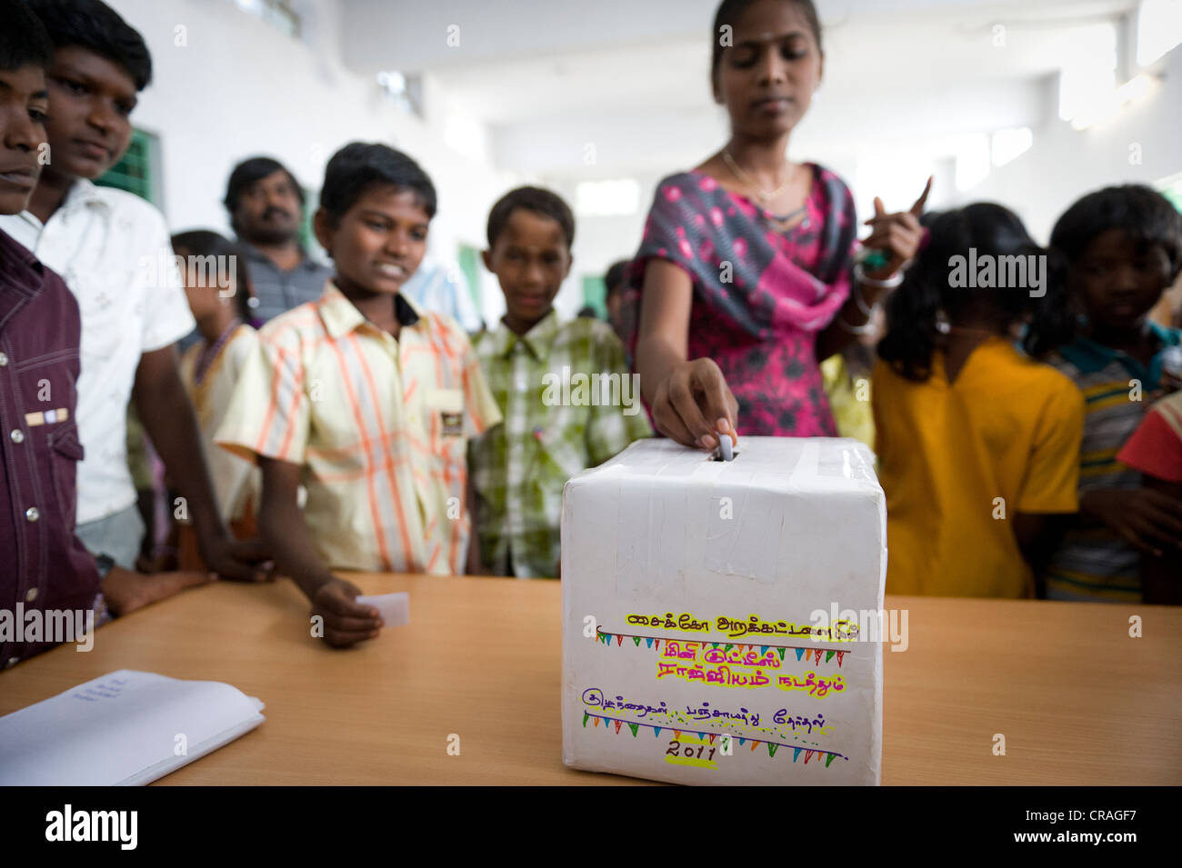 Ragazza mettendo scrutinio nella casella di voto, mini Kutties Rajiyam, panchayat elezione, Noyyal Maravapalayam vicino Karur, Tamil Nadu Foto Stock