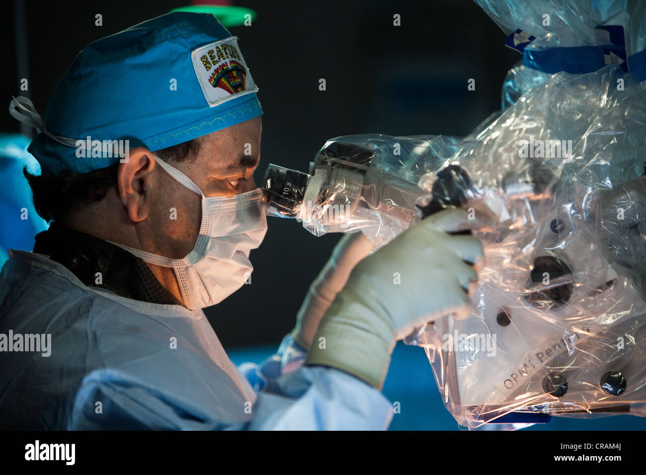 Un medico guarda attraverso un microscopio durante la chirurgia. Foto Stock