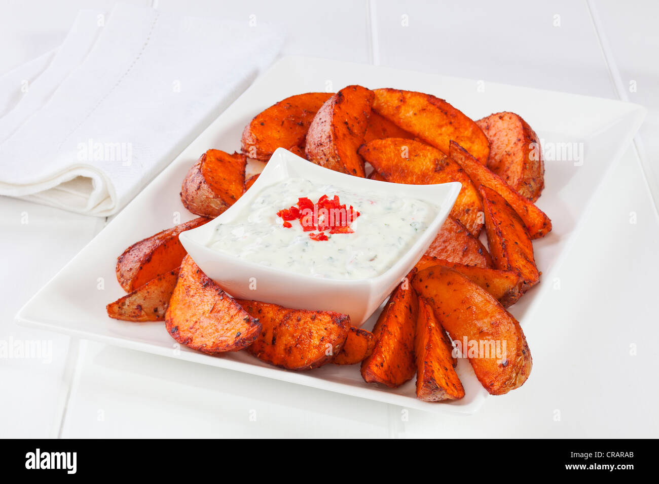 Speziato indiano Spicchi di patate con raita di cetriolo, su un piatto di bianco. Foto Stock