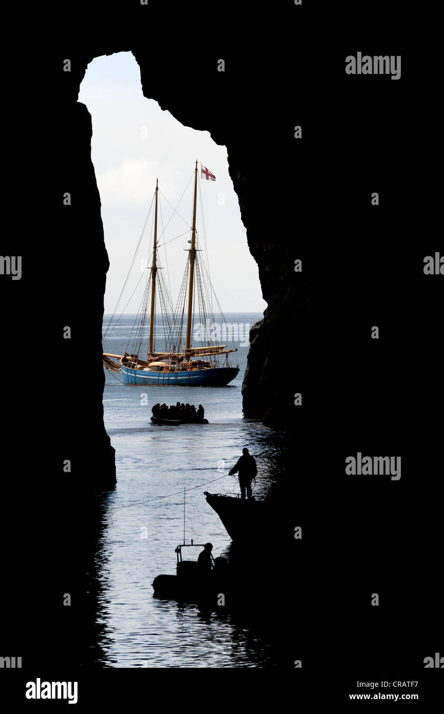 Vista dall'interno di una grotta verso una nave a vela, Norðlýsið, Hestur, Isole Faerøer, Atlantico del Nord Foto Stock