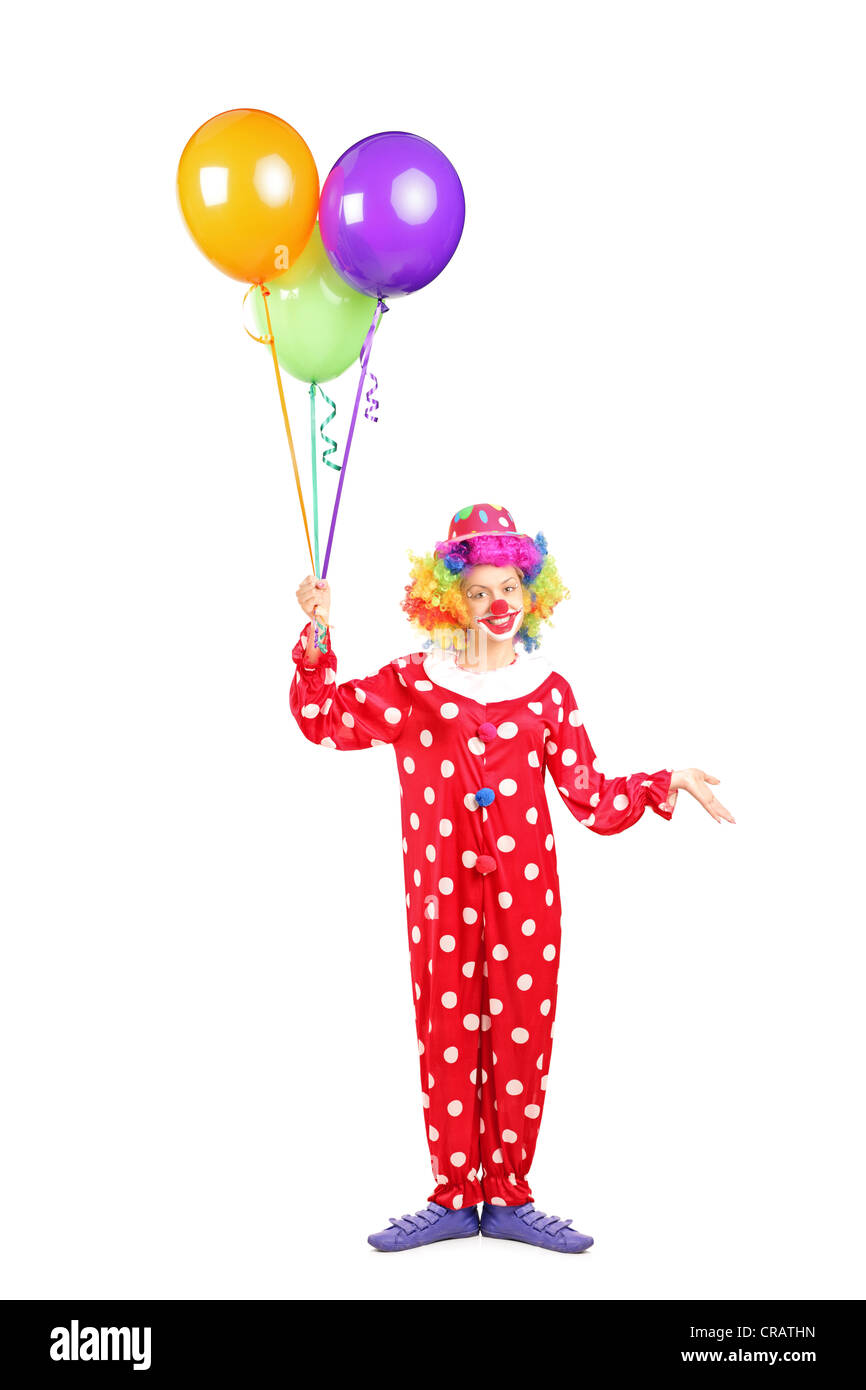 A piena lunghezza verticale di una femmina di clown, felice espressione gioiosa sul volto, con un mucchio di palloncini isolati su sfondo bianco Foto Stock
