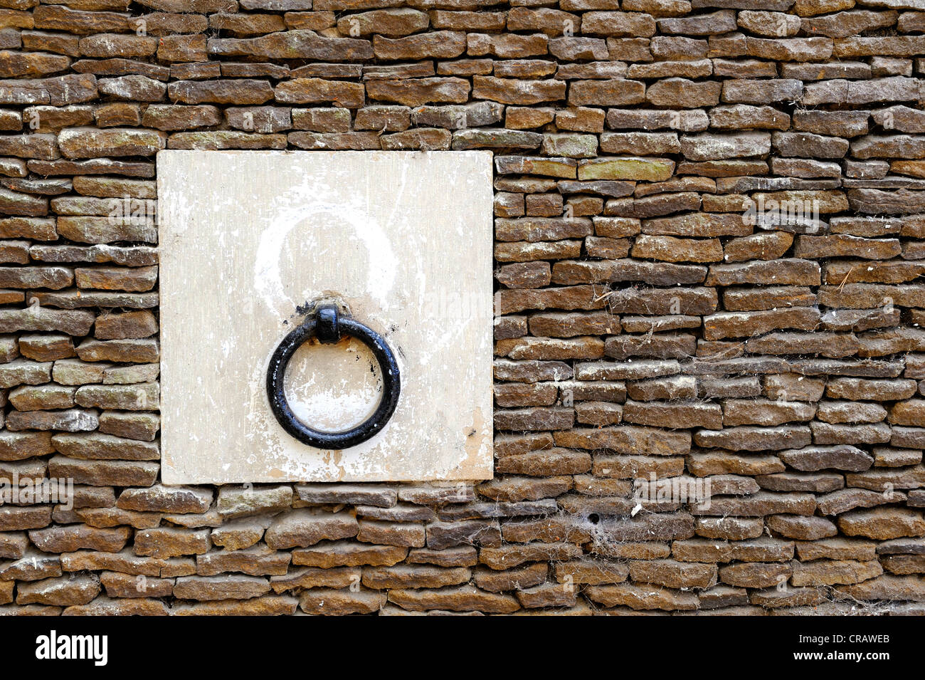 Anello metallico montato in un blocco di calcare e cementato in un muro di pietra Foto Stock