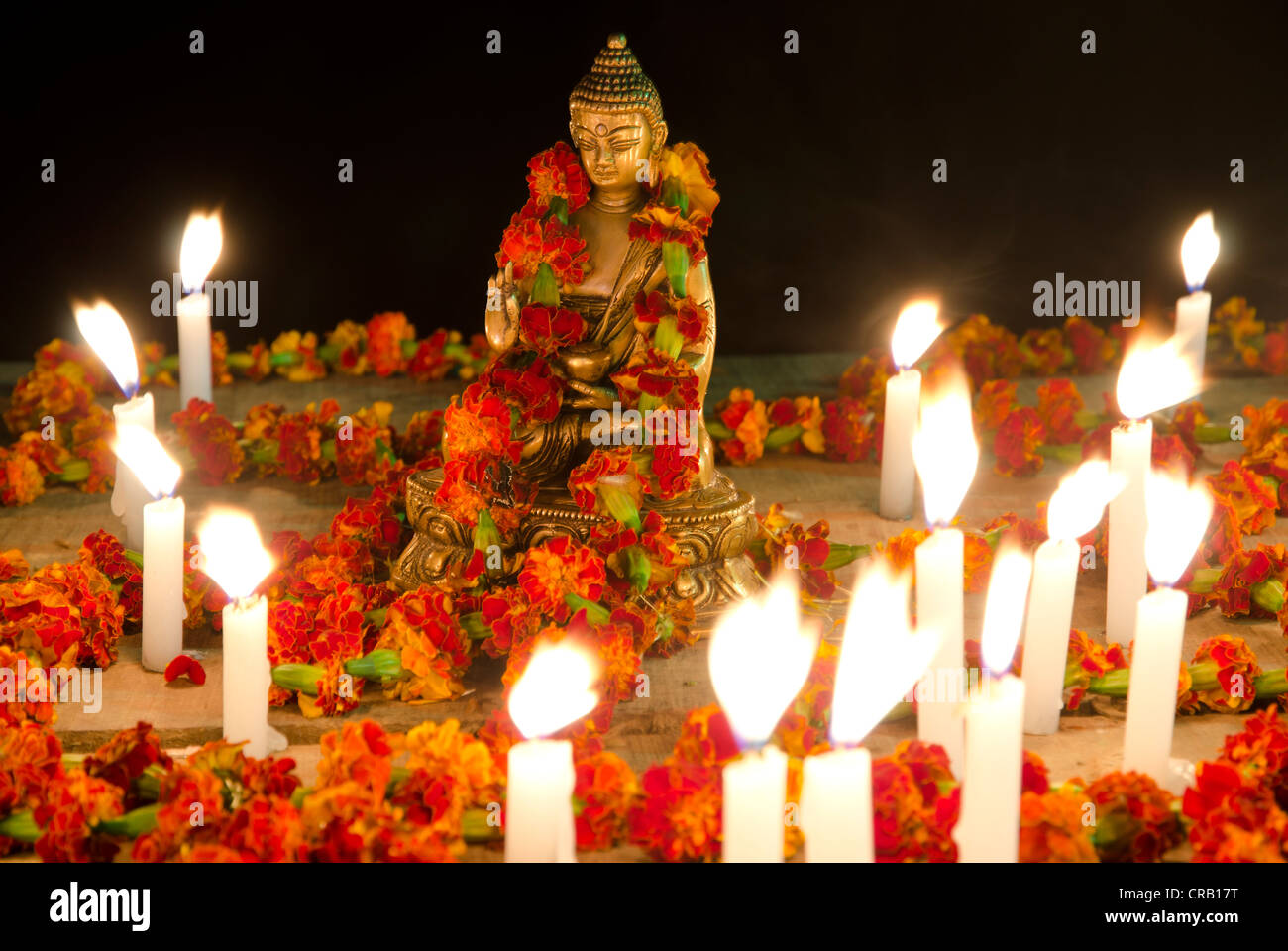 Statua di Buddha Shakyamuni, decorata con ilo e circondata da candele accese, sulle rive del Gange, Varanasi Foto Stock