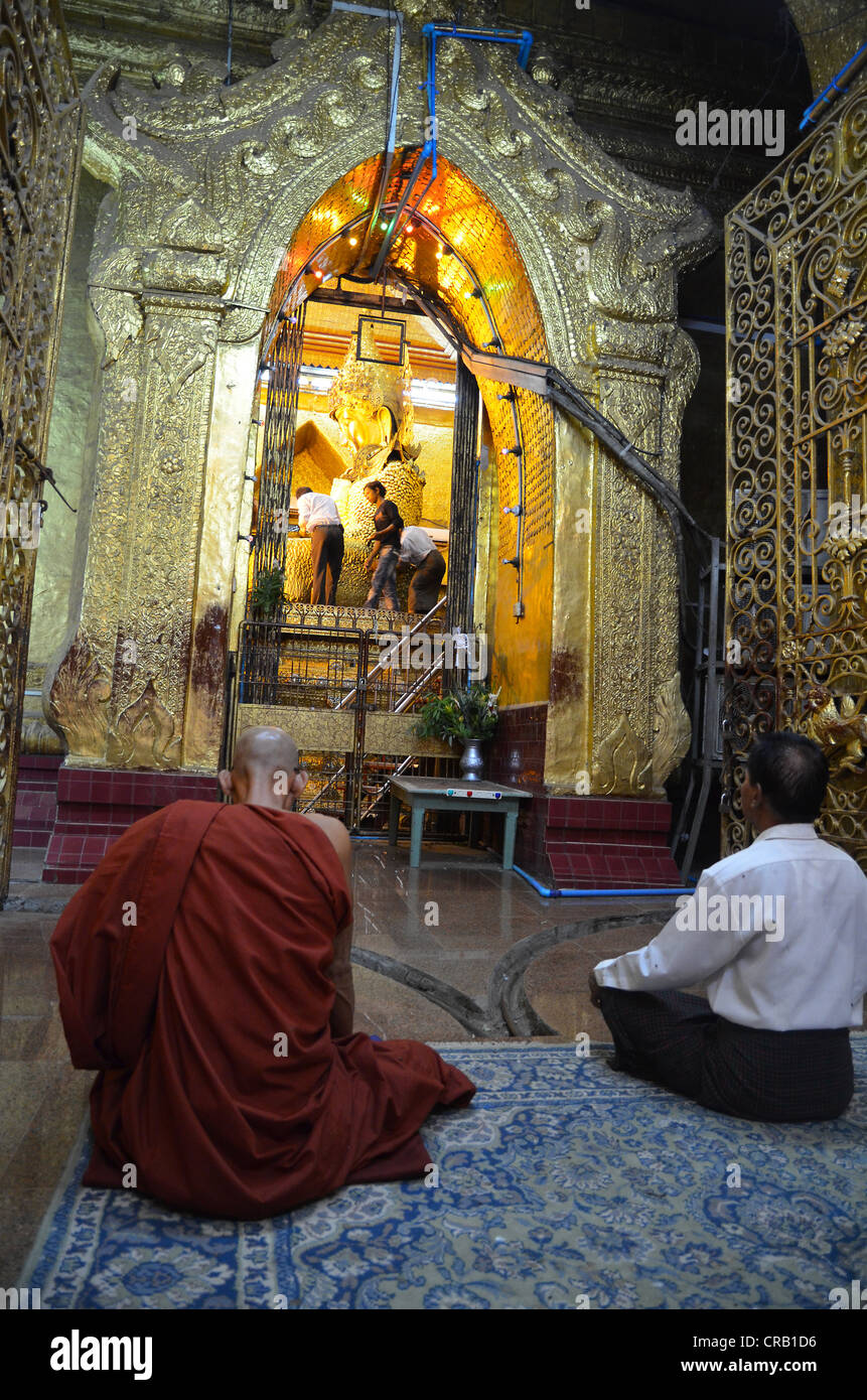Monaco birmano e un devoto anziano uomo seduto in preghiera di fronte al Santissimo statua del Buddha del paese, il golden Foto Stock