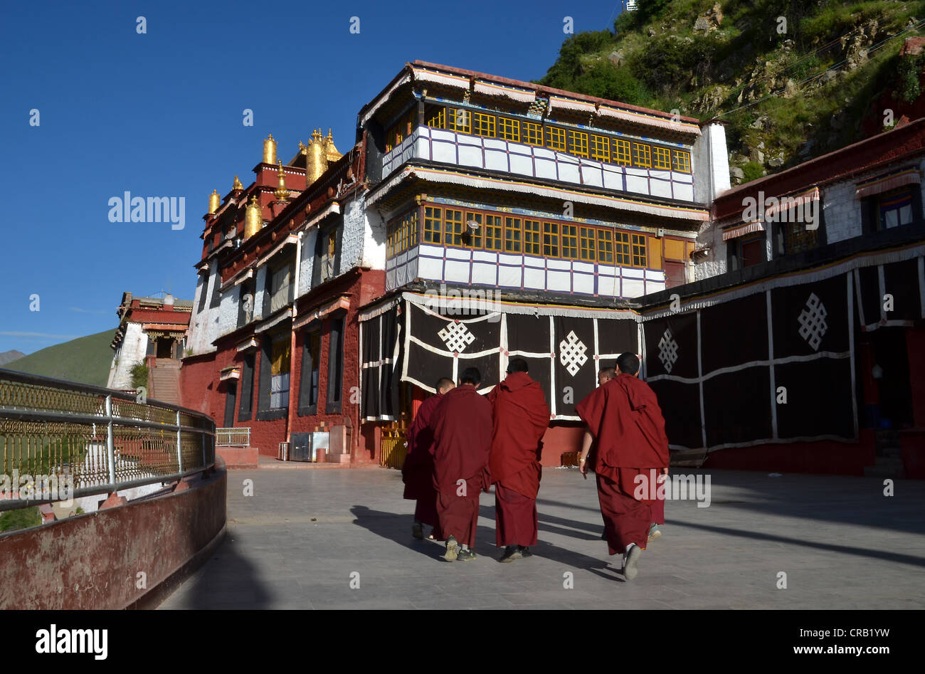 Monaci Tibetani indossando red tonaca di monaco entrando nella sala del monastero di Drigung, Drigung Til, Himalaya Foto Stock