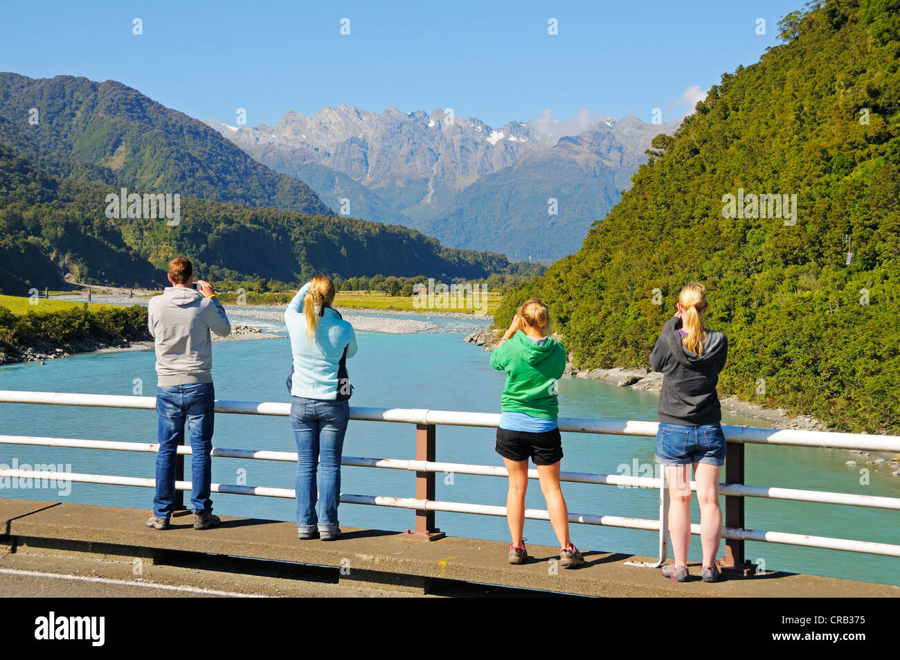 I turisti scattano fotografie del Fiume Whataroa, guardando verso il sud delle Alpi, Costa Ovest dell'Isola del Sud della Nuova Zelanda Foto Stock