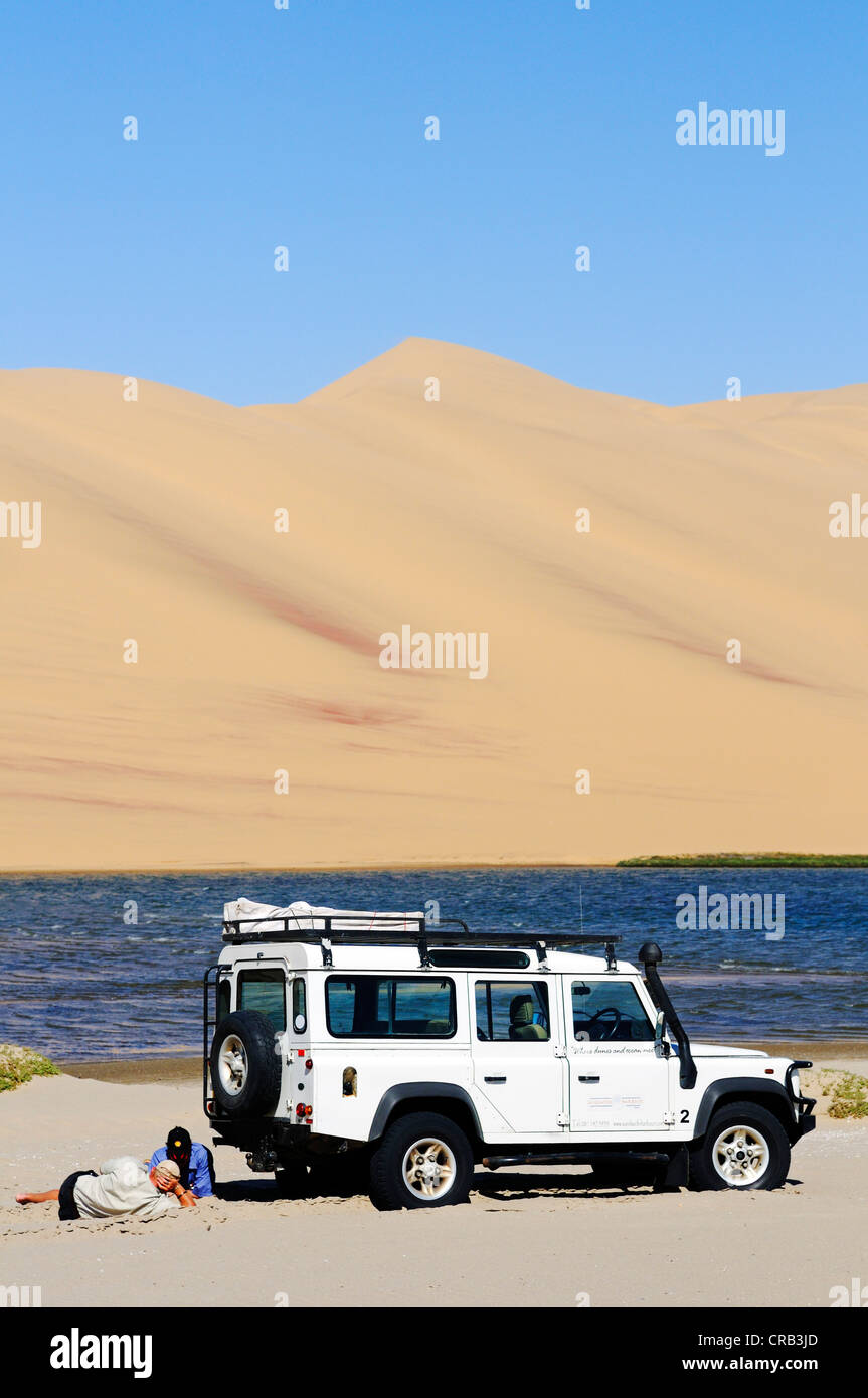 Gli uomini con un Landrover Defender veicolo fuoristrada in zone umide di Sandwich Harbour, Namib-Naukluft National Park Foto Stock