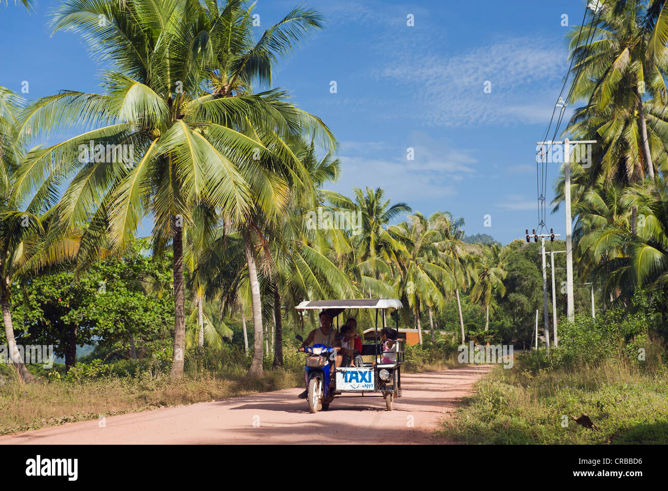 Un tuk tuk motociclo taxi guida su strada isola attraverso gli alberi di palma, Golden Pearl Beach, Ko Jum o Koh Pu isola, Krabi, Thailandia Foto Stock