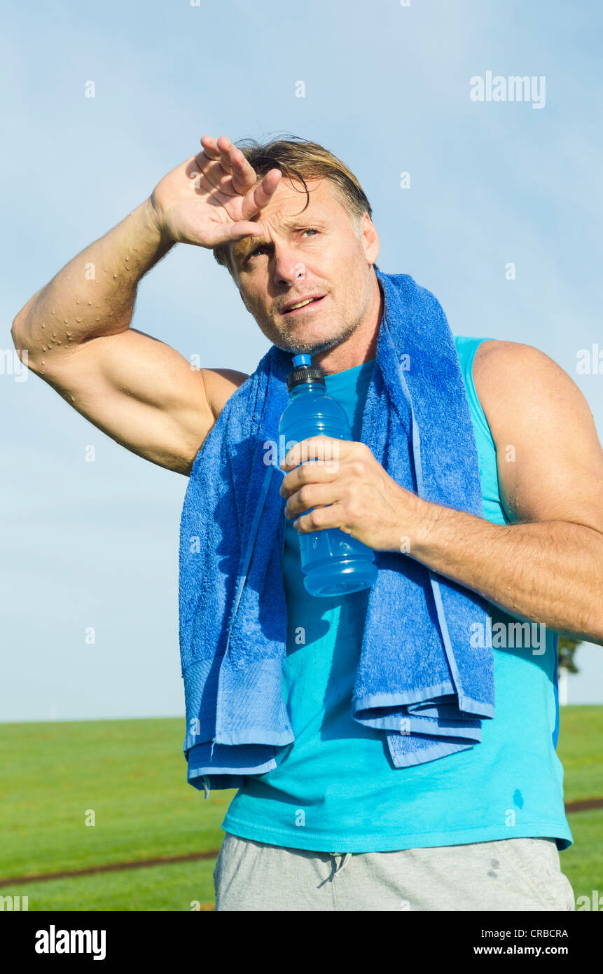 Un ritratto di una bella coppia sportivo nei suoi anni quaranta cercando stanchi di sete e sudate e tenendo una bottiglia di acqua in mano Foto Stock