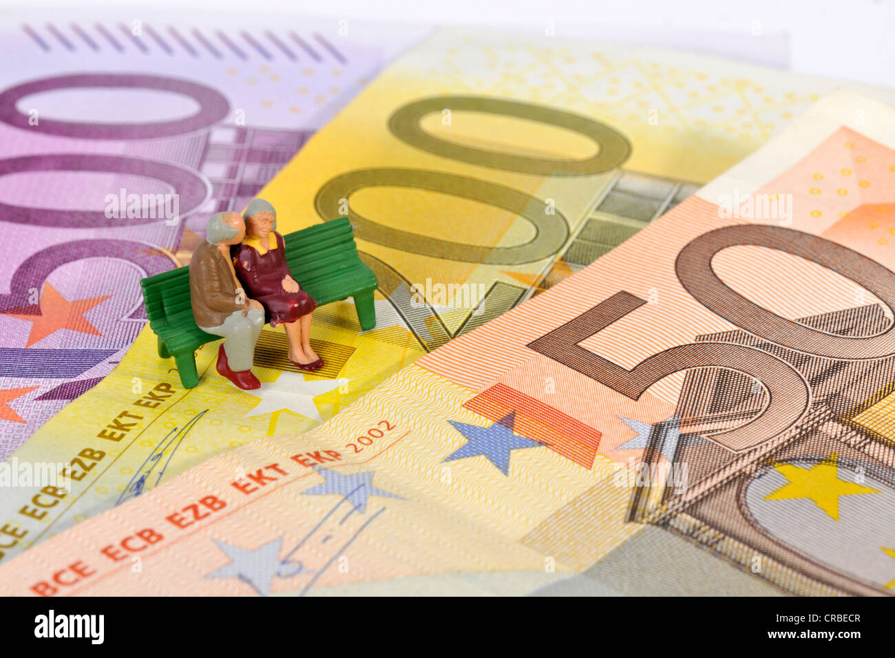Statuine in miniatura di un pensionato giovane seduto su una panchina nel parco sulle banconote in euro, immagine simbolica per il pensionamento, pension Foto Stock