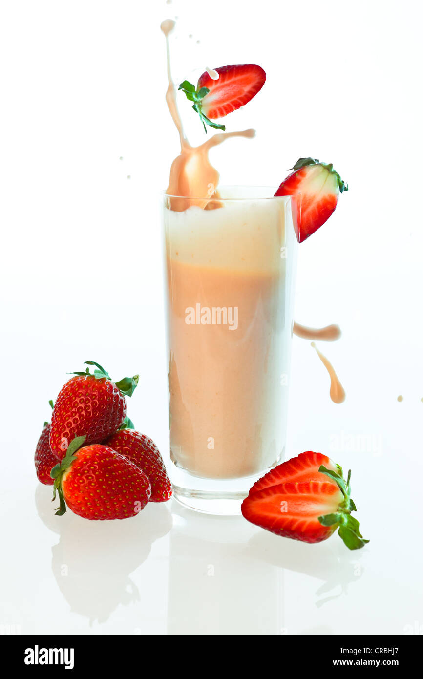 Le fragole che sta crollando in una fragola yogurt drink, frullato di fragole in un bicchiere Foto Stock