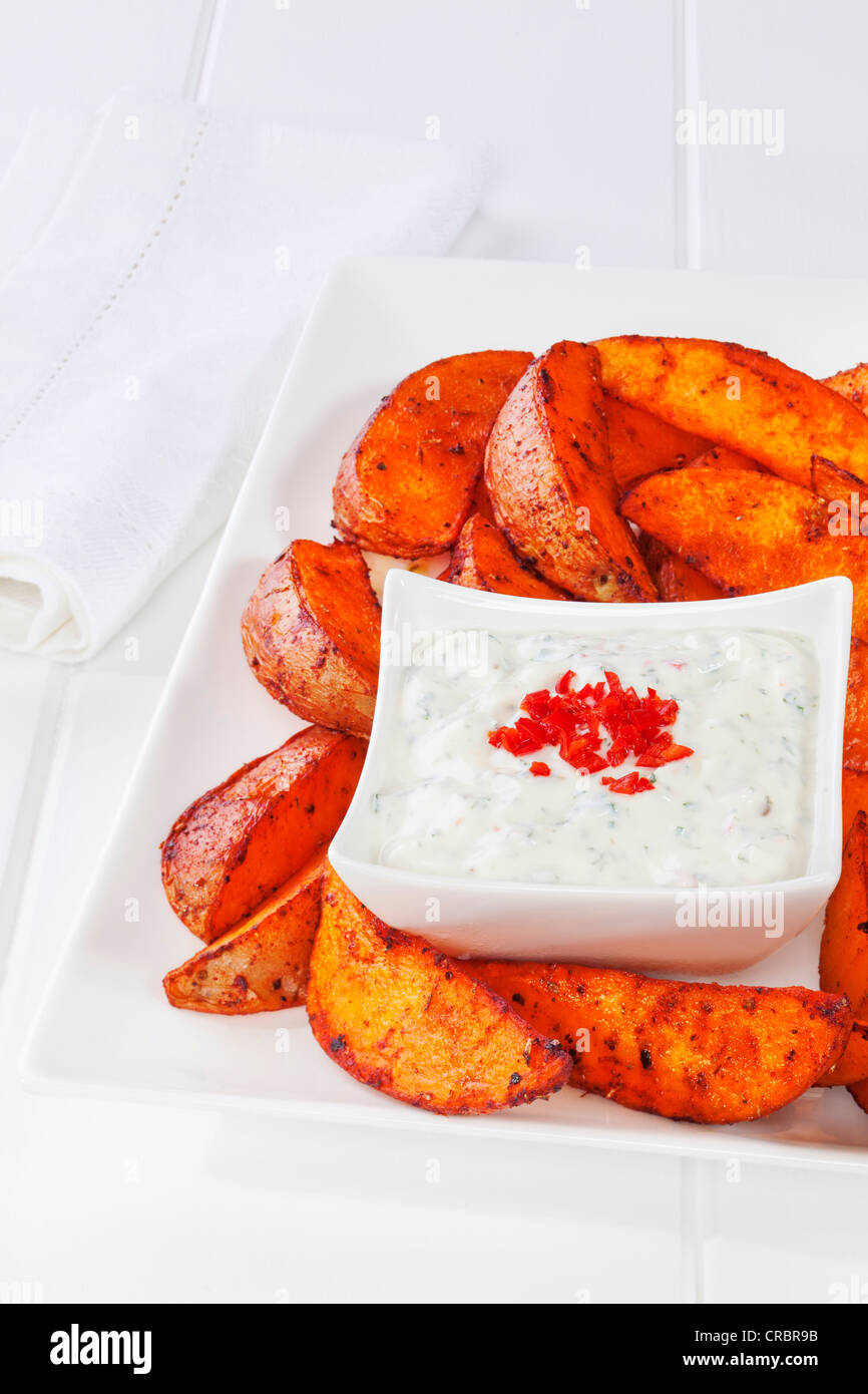 Speziato indiano Spicchi di patate con raita di cetriolo, su un piatto di bianco. Foto Stock