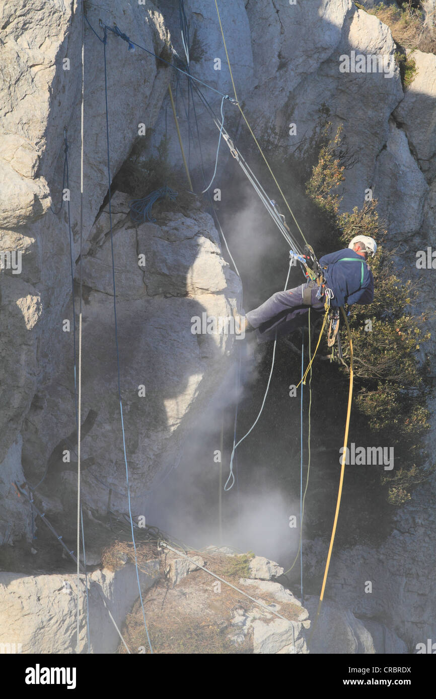 Lavoratori la salvaguardia di una scogliera con i martelli pneumatici contro frane, sciolto roccia viene eiettato fuori, La Turbie sopra il Principato di Monaco, Dipartimento Foto Stock