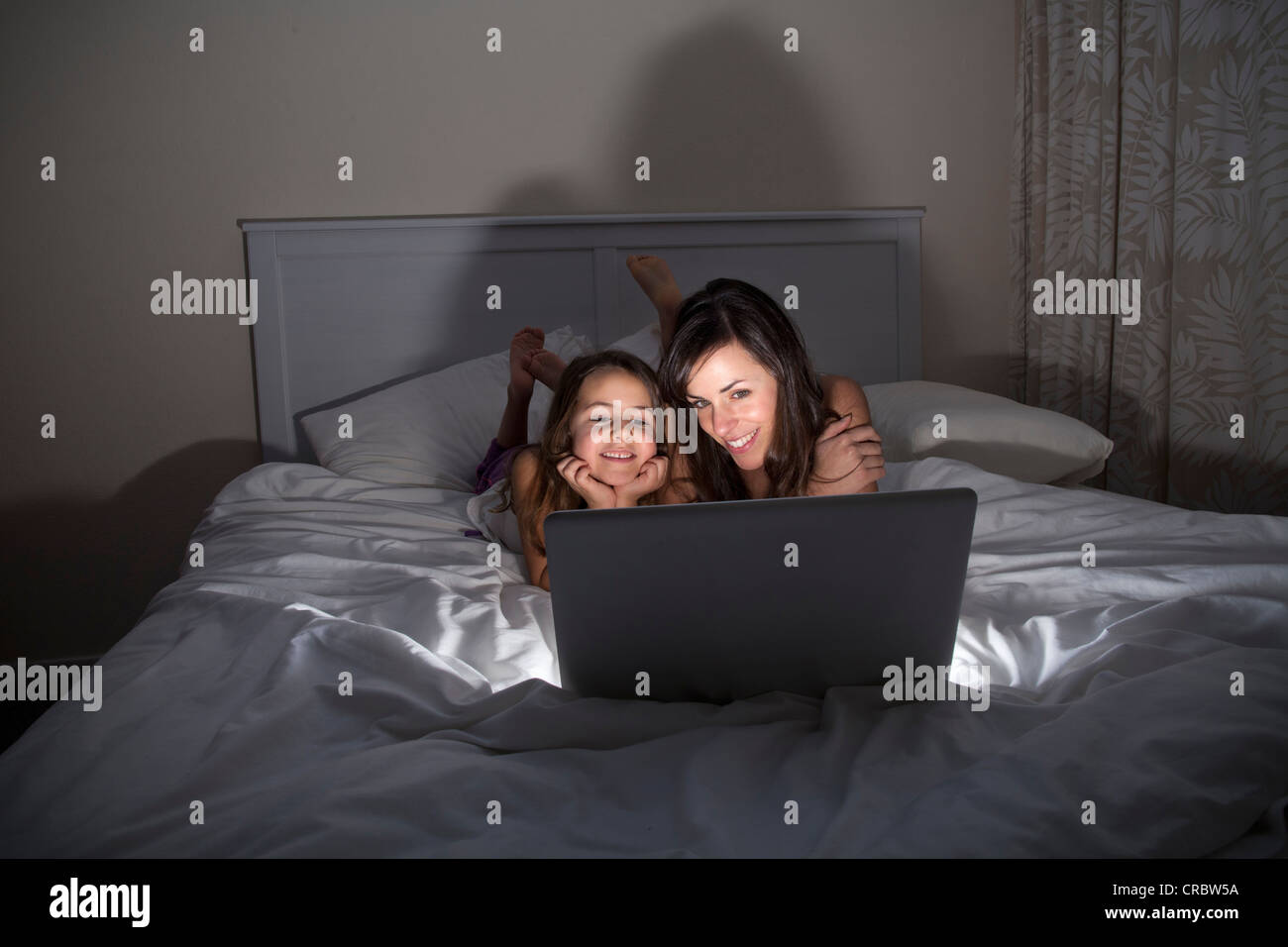Madre e figlia utilizzando laptop a letto Foto Stock