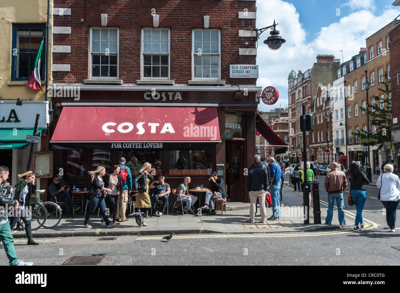 Soho Londra angolo di strada in scena con la Costa Coffee shop e le persone al di fuori in Old Compton Street in una giornata di sole Foto Stock
