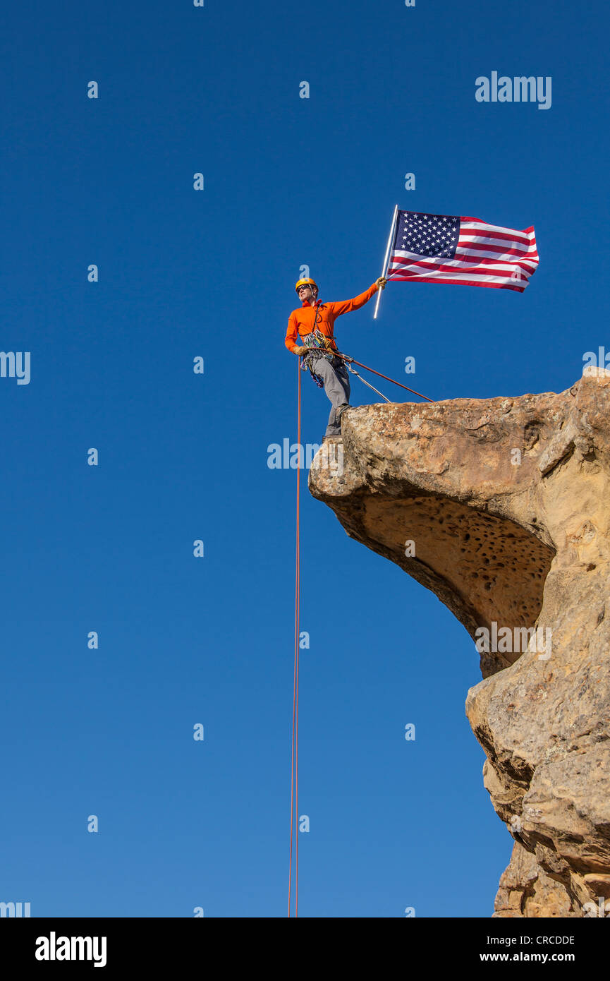 Scalatore onde una bandiera americana dal vertice dopo una impegnativa salita. Foto Stock