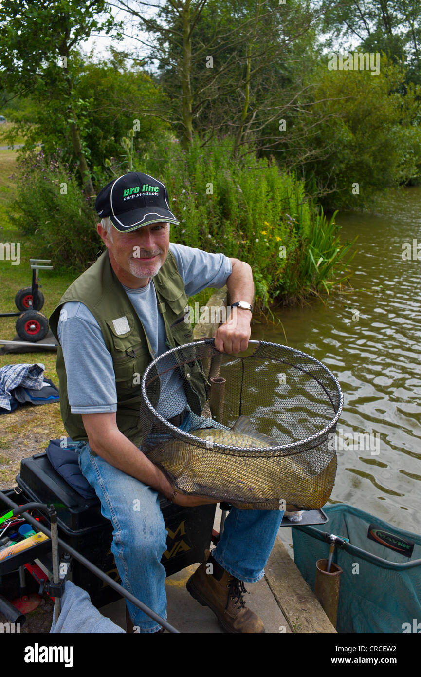 Il pescatore con una grande carpa in suo landing net Foto Stock