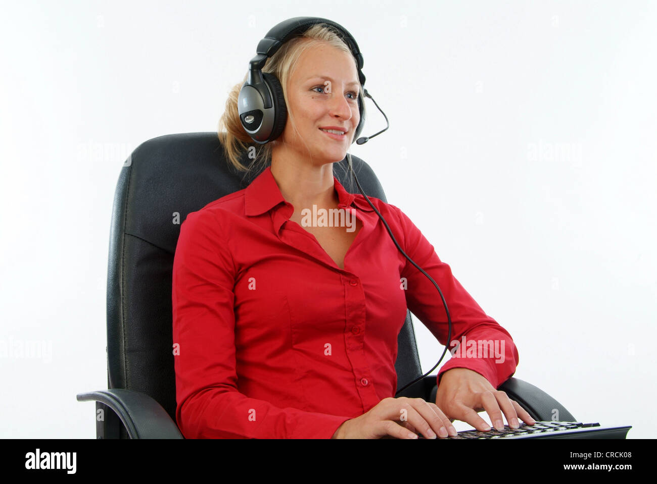 Giovane donna bionda con cuffie e tastiera sul giro Foto Stock