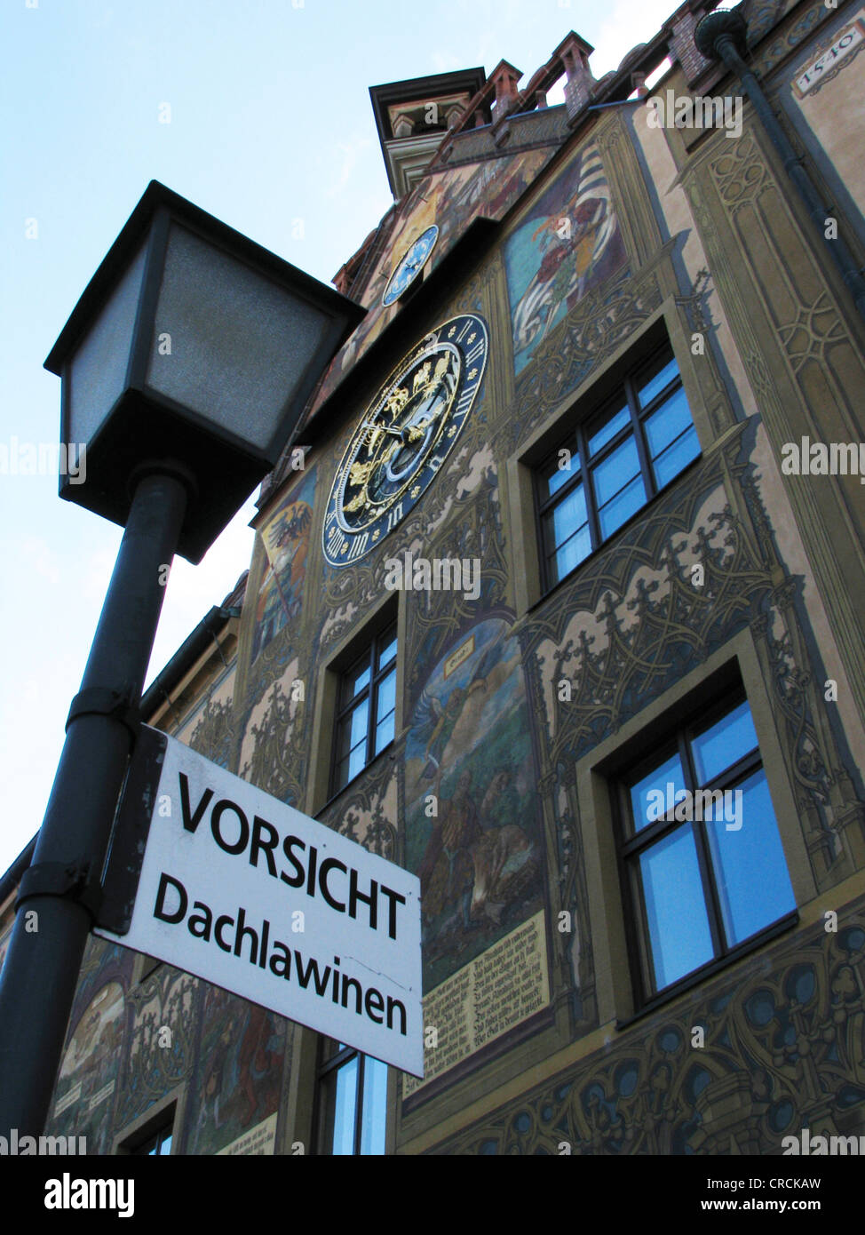Cartello con la scritta "Attenzione Valanghe dal tetto' davanti a una casa con un vecchio e parete artistica con un magnifico orologio da parete, Germania, Baden-Wuertemberg, Ulm Foto Stock