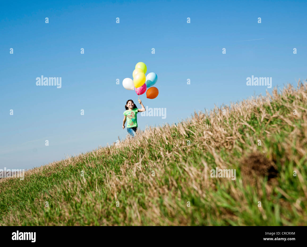 Ragazza che corre in prato con palloncini Foto Stock