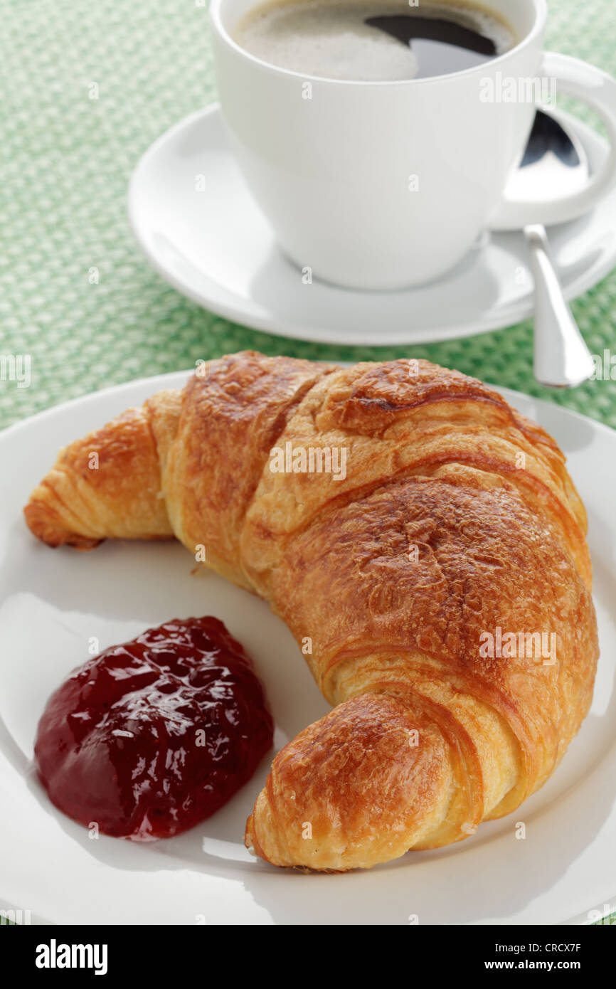 Croissant con confettura di fragole e una tazza di caffè Foto Stock