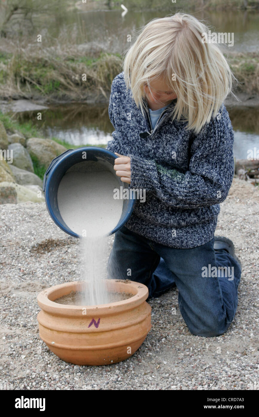 Bambini ritocchi un sun dial, vaso è riempito con sabbia, serie immagine 2/7 Foto Stock