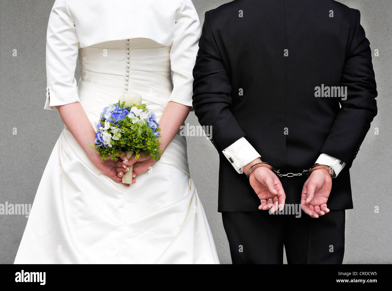 Coppie in viaggio di nozze visto da dietro la sposa è in possesso di un bouquet nuziale, lo sposo indossa manette Foto Stock
