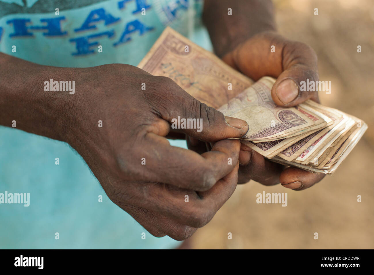 Un uomo conta i soldi che ha appena ricevuto da una cassa sociale programma di trasferimento nel villaggio di Julijuah, Contea Bomi, Liberia Foto Stock
