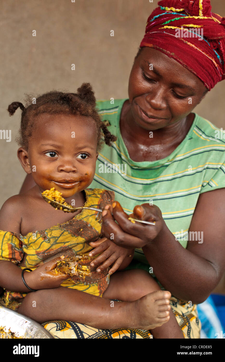 Jenneh Johnson, 31, alimenta la figlia Jusu, 2, a casa nel villaggio di Julijuah, Contea Bomi, Liberia Foto Stock