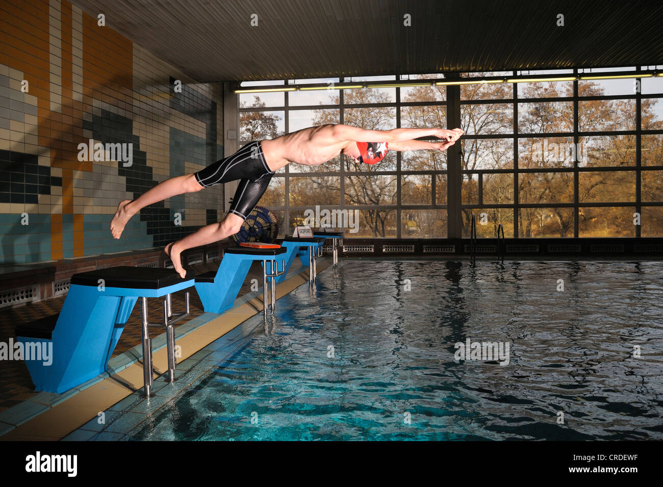 Il ragazzo, nuotatore, dodici o tredici anni, saltando dal blocco di partenza in piscina Foto Stock