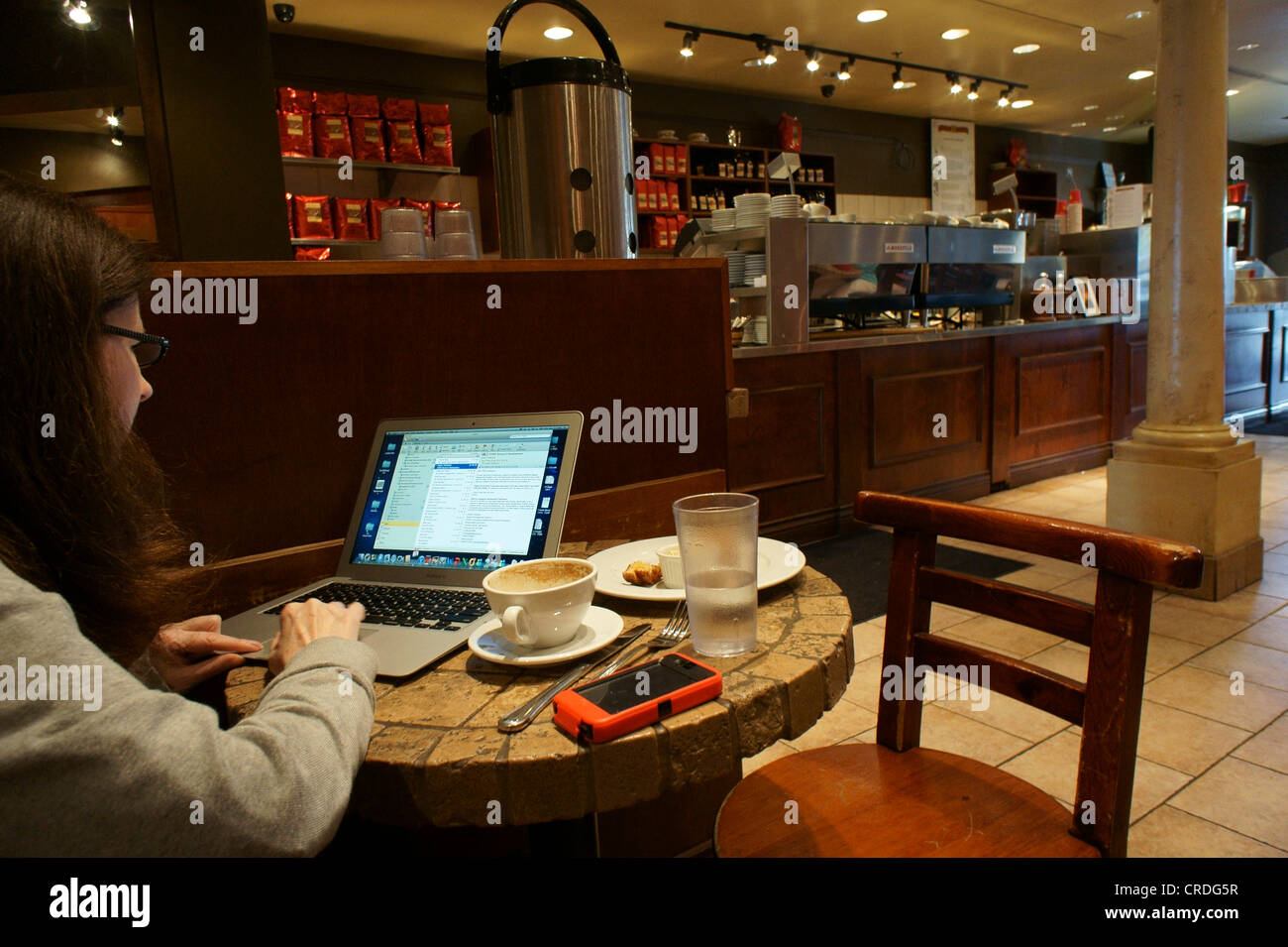 Donna che usa un computer portatile in una caffetteria Foto Stock