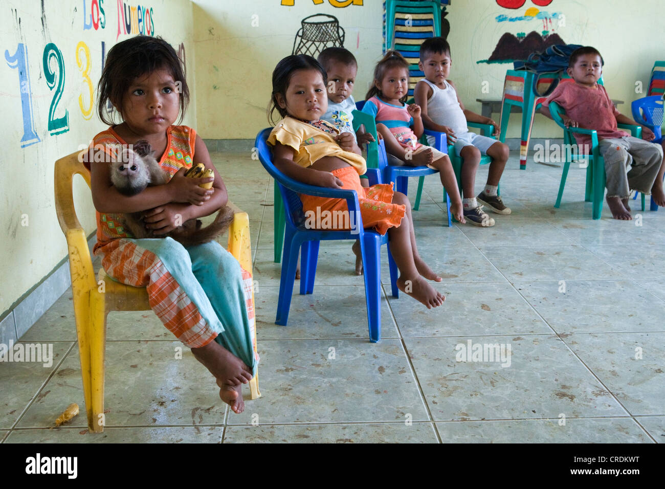 I bambini in età prescolare, una ragazza che è in possesso di una scimmia tame nelle sue braccia, in una scuola elementare in un villaggio con nessun accesso stradale Foto Stock
