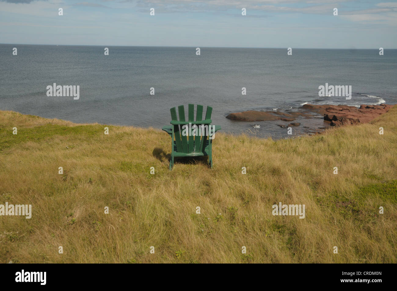 Una sedia si siede in cima alla scogliere rosso in Hermanville, Prince Edward Island, Canada. Foto Stock