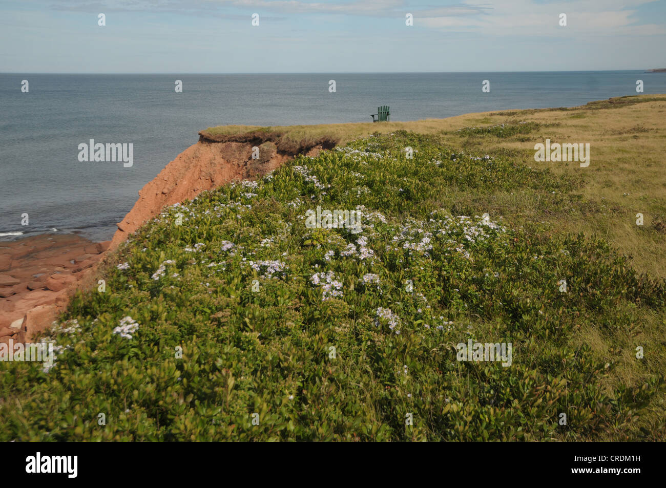 Una sedia si siede in cima alla scogliere rosso in Hermanville, Prince Edward Island, Canada. Foto Stock