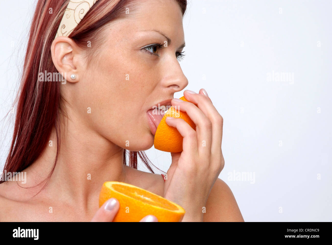 Giovane donna leccare presso un Orange Foto Stock